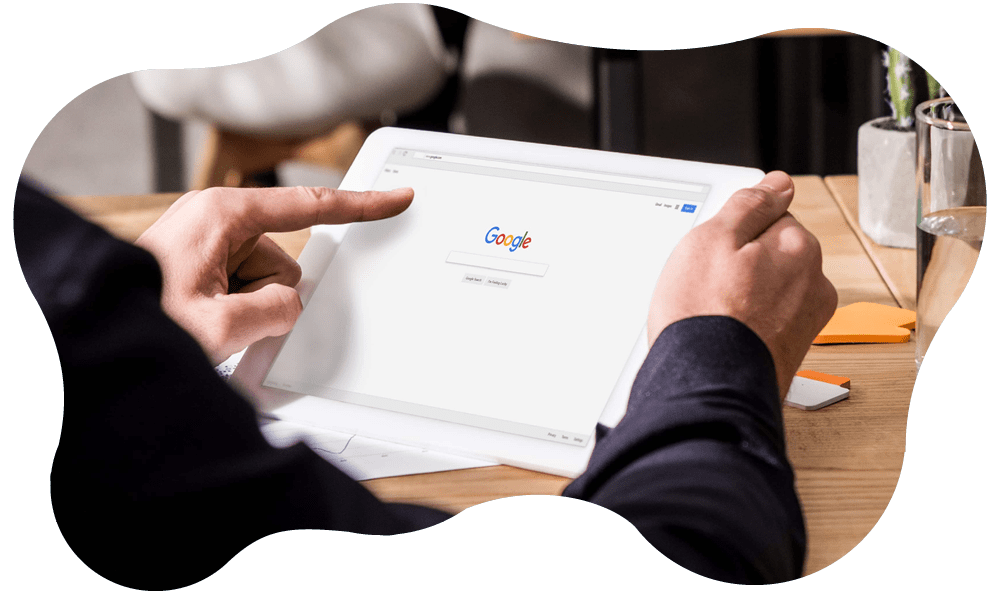 Fotografia del dettaglio di mani che impugnano un tablet sul cui schermo compare schermata di Google