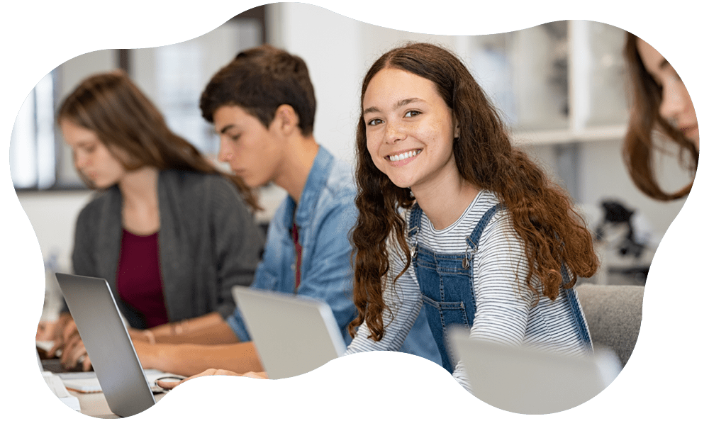 Fotografia di una serie di adolescenti in classe che guardano lo schermo di un computer mentre una di loro fissa in camera