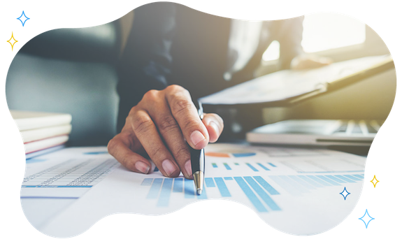 Fotografia di dettaglio di una mano che impugna una penna a sfera e indica alcuni grafici