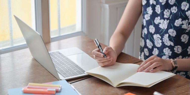 Fotografia di una insegnante che prende appunti davanti al computer