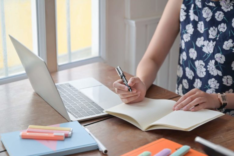 Fotografia di una insegnante che prende appunti davanti al computer