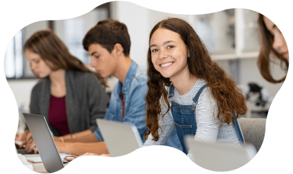 Fotografia di una serie di adolescenti in classe che guardano lo schermo di un computer mentre una di loro fissa in camera