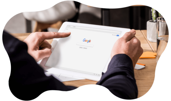 Fotografia del dettaglio di mani che impugnano un tablet sul cui schermo compare schermata di Google