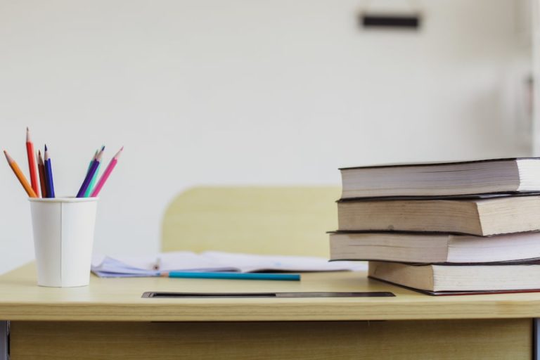 Fotografia di un banco scolastico con libri, portapenne e quaderni aperti