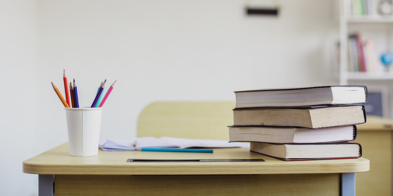 Fotografia di un banco scolastico con libri, portapenne e quaderni aperti