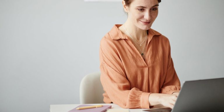 Fotografia di insegnante che lavora sorridente al suo computer portatile